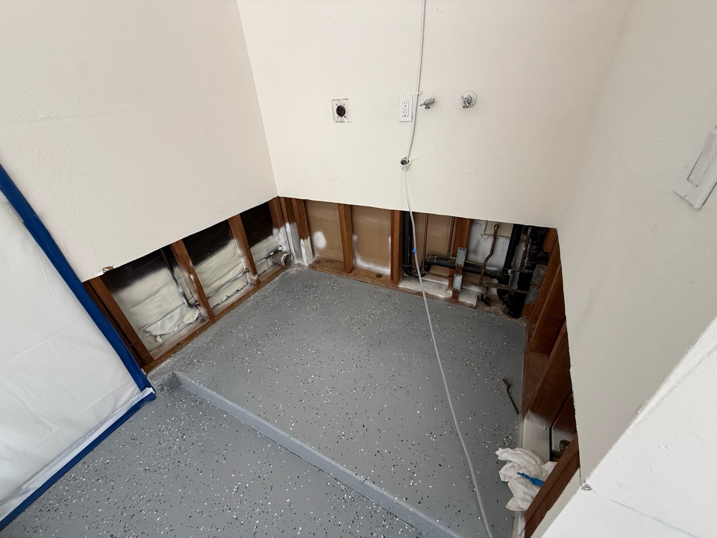 Laundry area with clean flood cuts, exposed studs, and sealed floor after drying